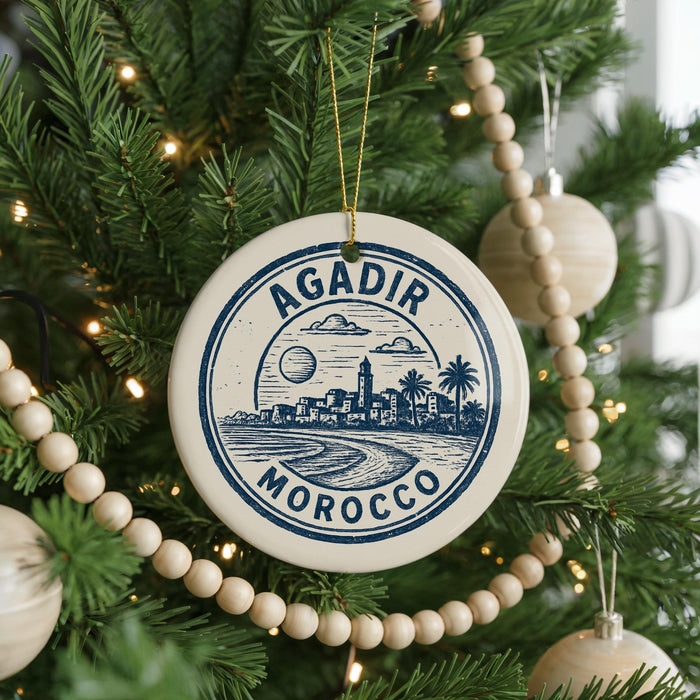 A circular ornament on a Christmas tree, featuring a cityscape and palm trees, with the text "AGADIR MOROCCO" printed on it.