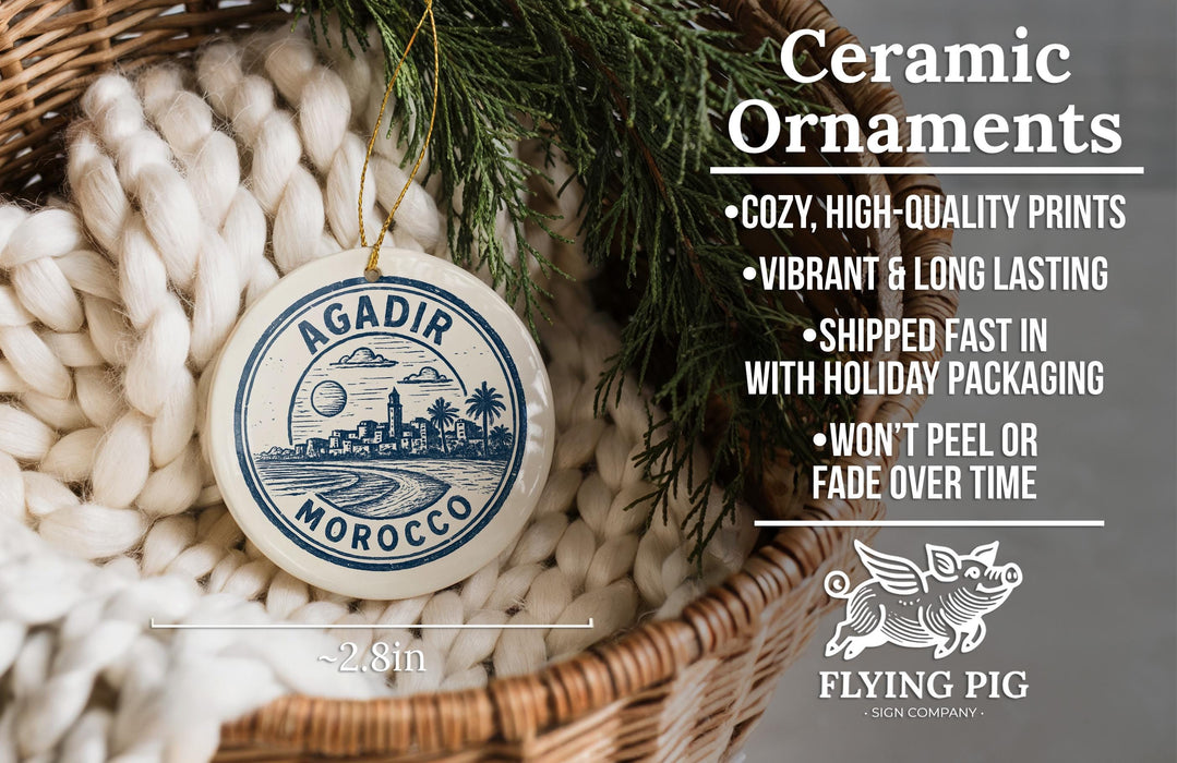 Ceramic ornaments, featuring a round ornament with a cityscape design, are displayed in a woven basket.