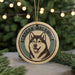 A circular ornament featuring a black and white illustration of a husky dog, with the text "Alaskan Malamute" written around the edge.