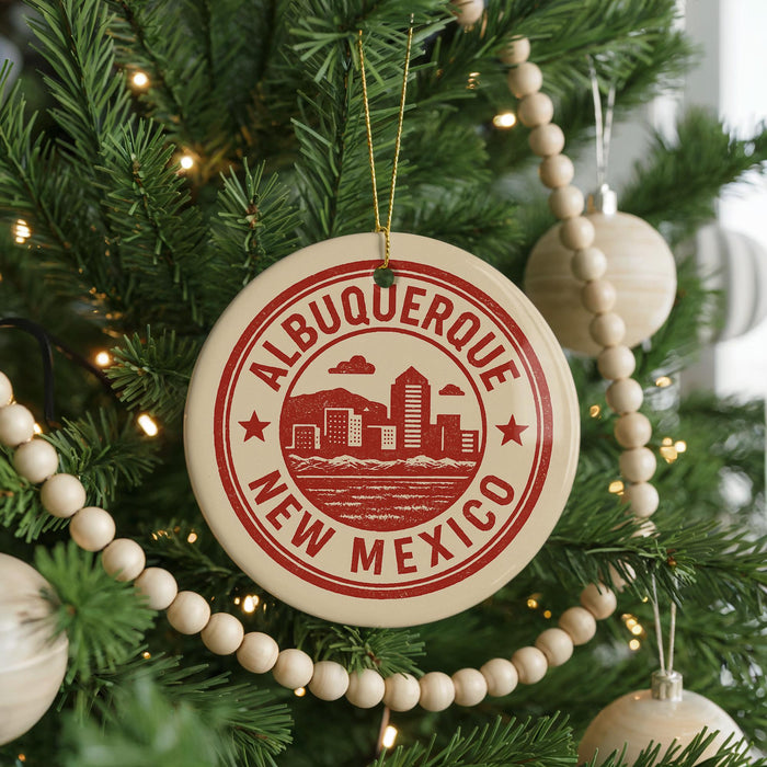 A Christmas tree decorated with ornaments, including a circular ornament with the text "ALBUQUERQUE NEW MEXICO" and a wooden bead decoration.