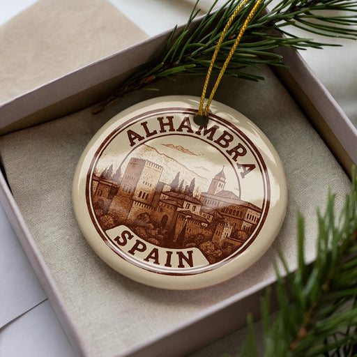 A decorative ornament in a box, featuring a circular design with a cityscape and text that reads "ALHAMBRA SPAIN".