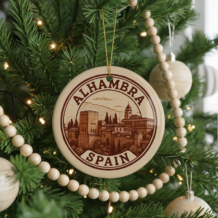 A circular ornament on a Christmas tree, featuring an illustration of a cityscape with a castle, surrounded by a border with the text "ALHAMBRA SPAN" in the center.