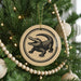 A Christmas tree decorated with ornaments, including a circular ornament featuring a graphic of a crocodile.