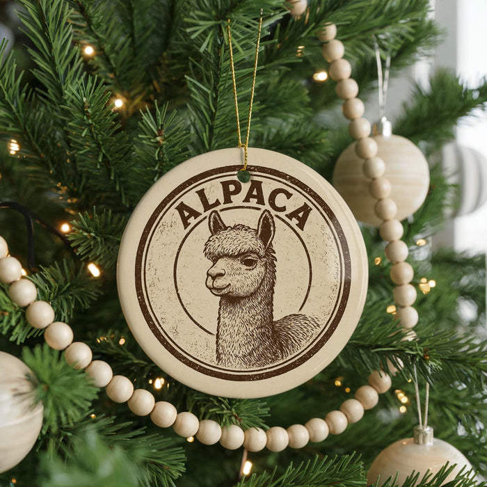 A Christmas tree decorated with ornaments, including a circular ornament with an image of an alpaca and the word "ALPACA" written on it.