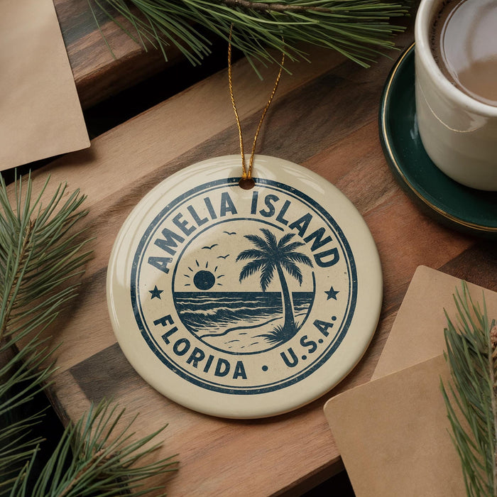 A circular ornament with the text "AMELIA ISLAND FLORIDA U.S.A." printed on it, surrounded by pine branches and a cup of coffee on a wooden surface.