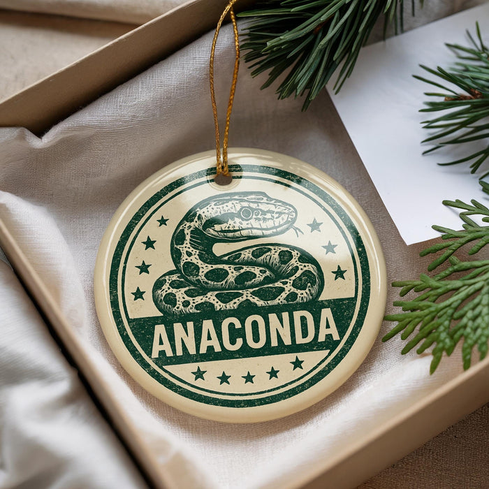 A round ornament with a snake design and the word "ANACONDA" printed on it, hanging from a string.