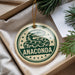 A round ornament with a snake design and the word "ANACONDA" printed on it, hanging from a string.