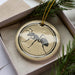 A ceramic ornament in a box, featuring a black and white illustration of a ant.