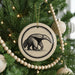 A Christmas tree decorated with ornaments, including a circular ornament featuring an illustration of an animal, and beaded ornaments.