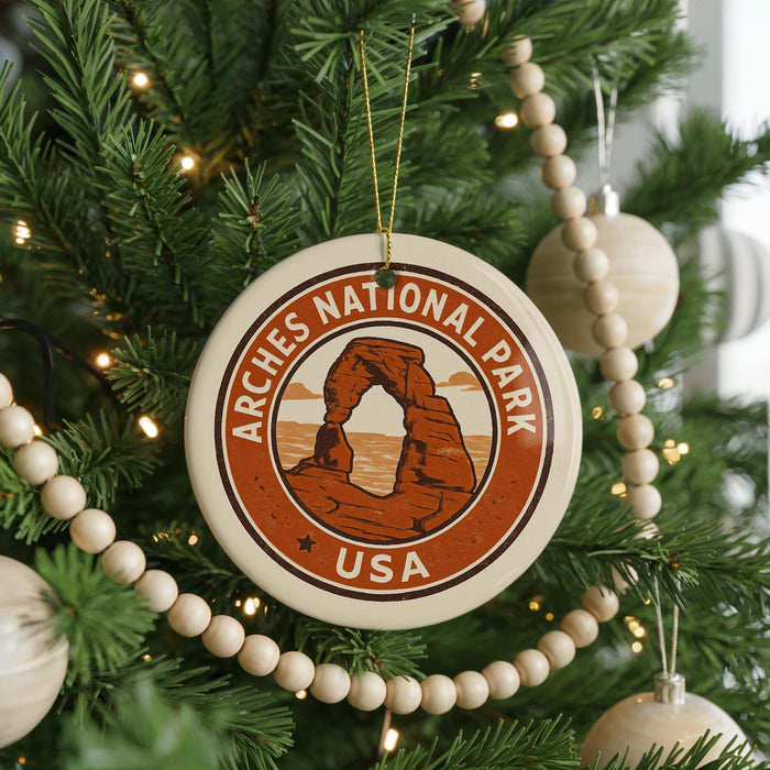 A Christmas tree decorated with ornaments, including a circular ornament with the text "ARCHES NATIONAL PARK USA" and a graphic of a rock formation.