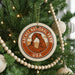 A Christmas tree decorated with ornaments, including a circular ornament with the text "ARCHES NATIONAL PARK USA" and a graphic of a rock formation.