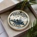 A circular ornament with the text "ARLINGTON TEXAS U.S.A." printed on it, surrounded by pine branches.