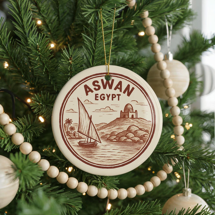 A Christmas tree decorated with ornaments, including a circular ornament with a sailboat and the text "ASWAN EGYPT" on it.