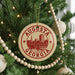 A Christmas tree decorated with ornaments, including a circular ornament with the text "AUGUSTA GEORGIA" and a wooden bead decoration.