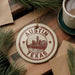 A circular ornament with the text "AUSTIN TEXAS" and a cityscape illustration, hanging on a wooden surface.