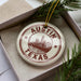 A circular ornament with the text "AUSTIN TEXAS" printed on it, surrounded by a border of stars.