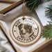 A circular ornament featuring an image of a dog, specifically an Australian Shepherd, with the text "AUSTRALIAN SHEPHERD" printed on it. The ornament is hanging from a string and is placed on a surface with some greenery visible in the background.