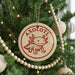 A Christmas tree decorated with ornaments, including a circular ornament with a red and white design featuring a cartoon axolotl.