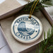 A circular ornament with the text "Baffin Island Canada" printed on it, surrounded by pine branches.