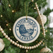 A Christmas tree decorated with ornaments, including a circular ornament with the text "Baffin Island Canada" and a mountain illustration.