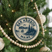 A Christmas tree decorated with ornaments, including a circular ornament with the text "BAR HARBOR Maine" and a sailboat illustration.