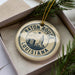 A circular ornament with the text "BATON ROUGE LOUISIANA" printed on it, surrounded by pine branches.