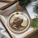 A ceramic ornament featuring a bearded dragon is displayed in a box, surrounded by pine branches.