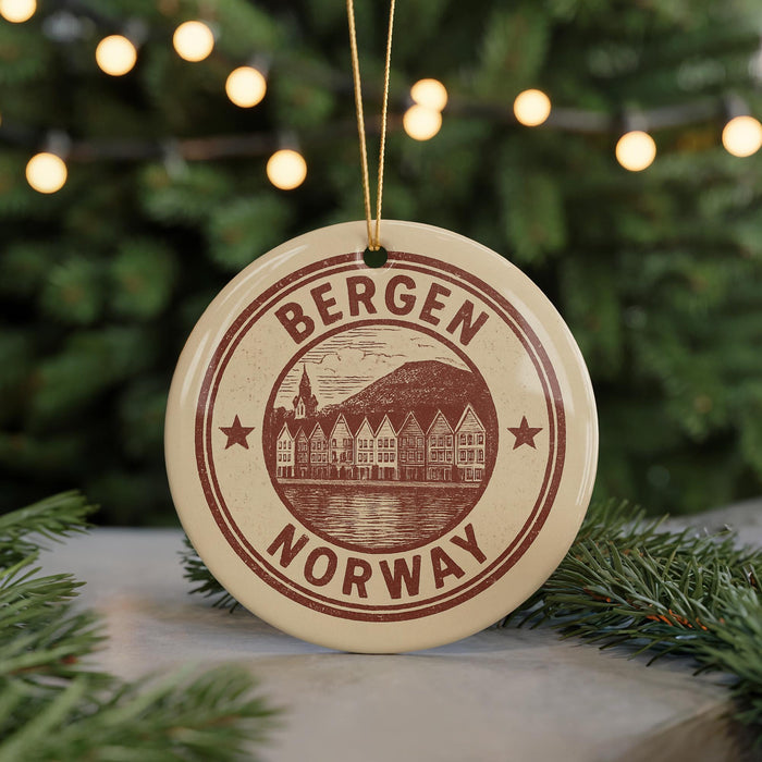 A circular ornament with the text "BERGEN NORWAY" printed on it, featuring a graphic of a town or village.