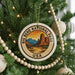 A Christmas tree decorated with ornaments, including a large circular ornament with the text "BIG BEND NATIONAL PARK USA" and a mountain landscape design.