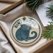 A circular ornament with a picture of a bear and the word "Binturong" on it, hanging from a string.