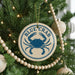 A Christmas tree decorated with ornaments, including a blue crab ornament with the text "BLUE CRAB" on it.