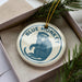 A ceramic ornament in a box, featuring a blue monkey illustration.