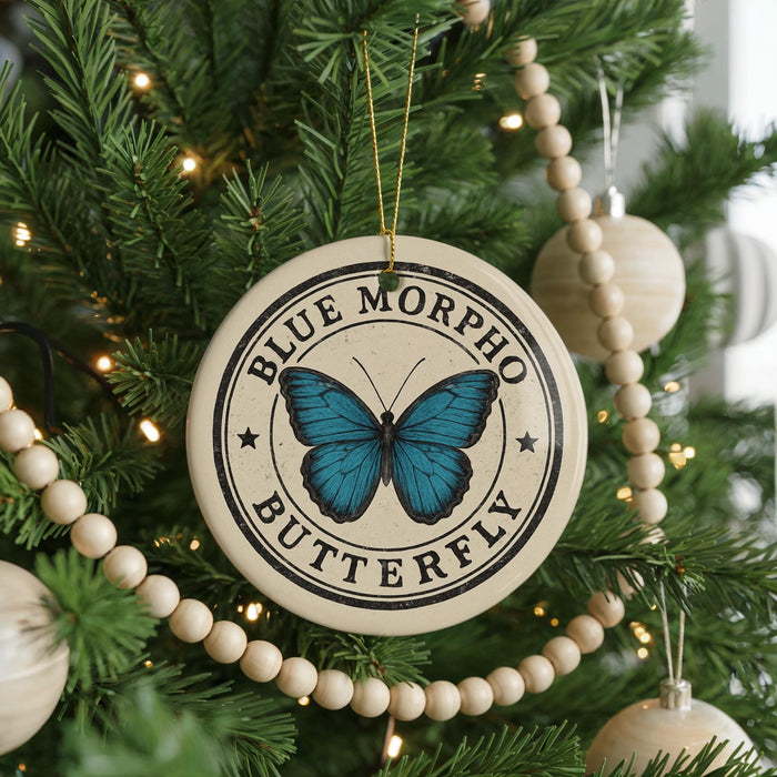 A circular ornament with a blue butterfly design hangs from a Christmas tree, surrounded by other ornaments and lights.