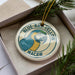 A decorative ornament in a box, featuring a parrot and the text "BLUE-AND-YELLOW MACAW".