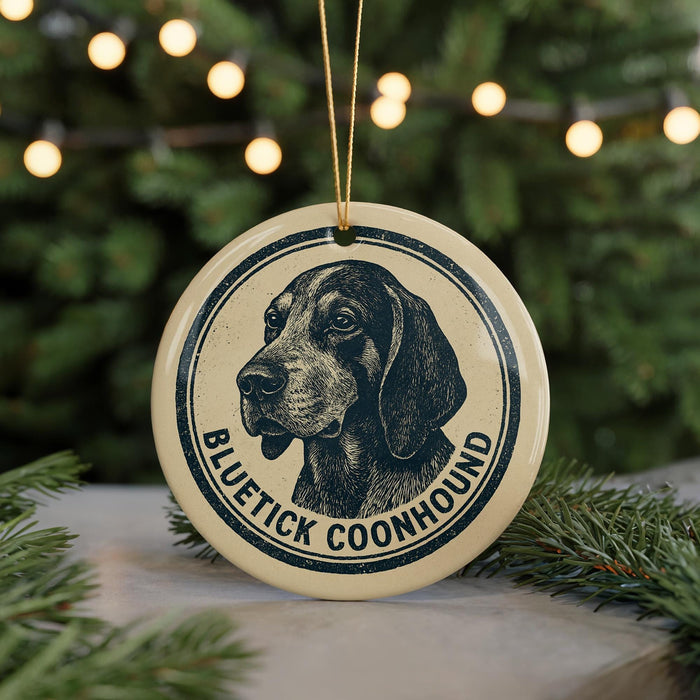 A circular ornament featuring a black and white illustration of a blue heeler dog, with the text "BLUEETICK COONHOUND" printed on it.