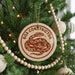 A Christmas tree decorated with ornaments, including a round ornament with a snake design and the text "BOA CONSTRICTOR" on it.
