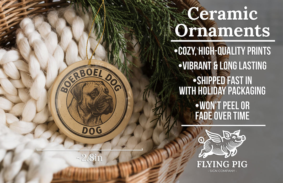 Ceramic ornaments, featuring a Börobel Dog ornament, are displayed in a woven basket with pine branches.