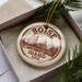 A circular ornament with the text "BOISE IDAHO USA" printed on it, surrounded by pine branches.
