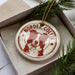 A white ceramic ornament with a red border and a picture of a Border Collie dog.
