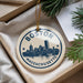 A circular ornament with the text "BOSTON MASSACHUSETTS" and a graphic of the Boston skyline, hanging from a string.