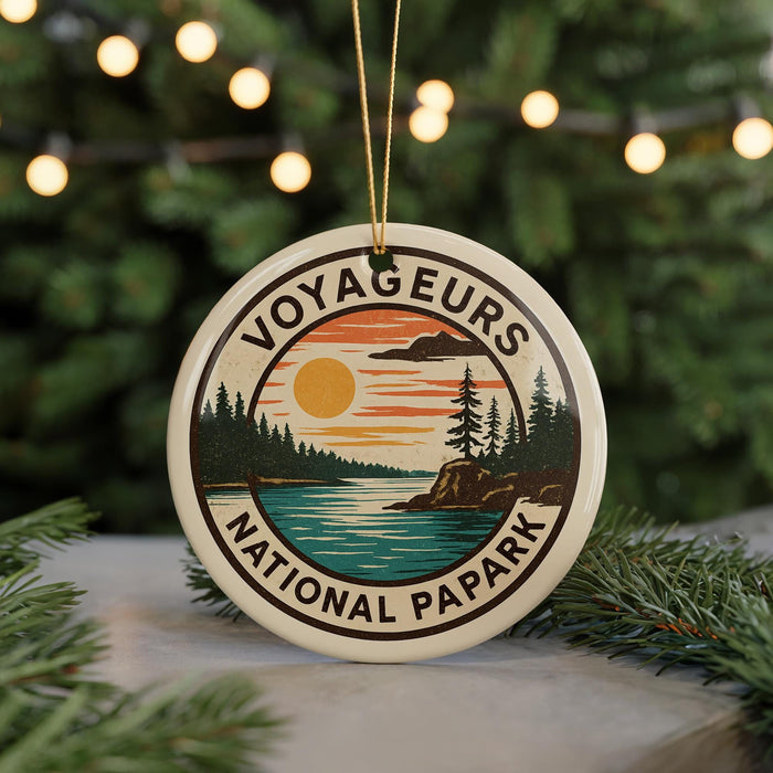 A circular ornament with the text "VOYAGEURS NATIONAL PAPARK" and an illustration of a sunset over a lake surrounded by pine trees.