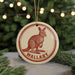 A circular ornament featuring a kangaroo, with the word "Wallaby" written below it, is hanging from a string.