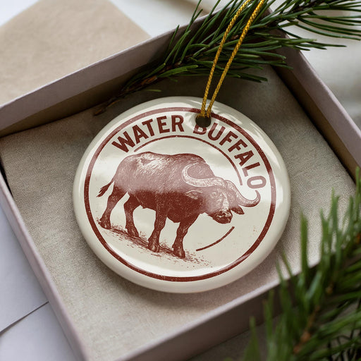 A circular ornament with the word "WATER" and a picture of a buffalo is displayed in a box, surrounded by pine branches.