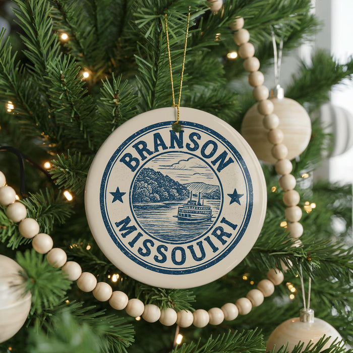 A Christmas tree decorated with ornaments, including a circular ornament with the text "BRANSON MISSOURI" and a boat illustration.