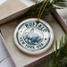 A decorative ornament in a box, featuring a circular design with a bison and the text "BUFFALO NEW YORK USA".