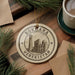A circular ornament with the text "BUKHARA UZBEKISTAN" and an illustration of a mosque, hanging on a wooden surface.
