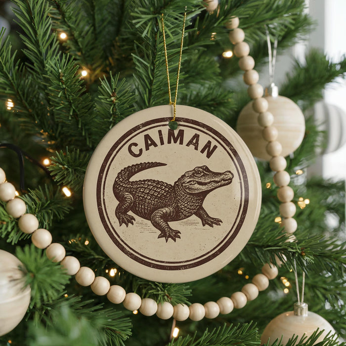 A Christmas tree decorated with ornaments, including a circular ornament with an image of an alligator and the word "CAIMAN" written on it.