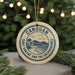 A circular ornament with a design featuring a beach and palm trees, surrounded by Christmas lights.