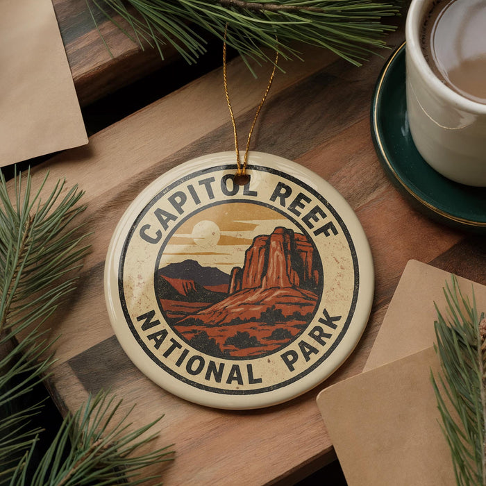 A decorative ornament featuring the Capitol Reef National Park logo, surrounded by pine branches and a cup of coffee on a wooden surface.