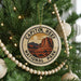 A circular ornament on a Christmas tree, featuring the text "CAPITOL REEF NATIONAL PARK" and an illustration of a desert landscape with mountains.